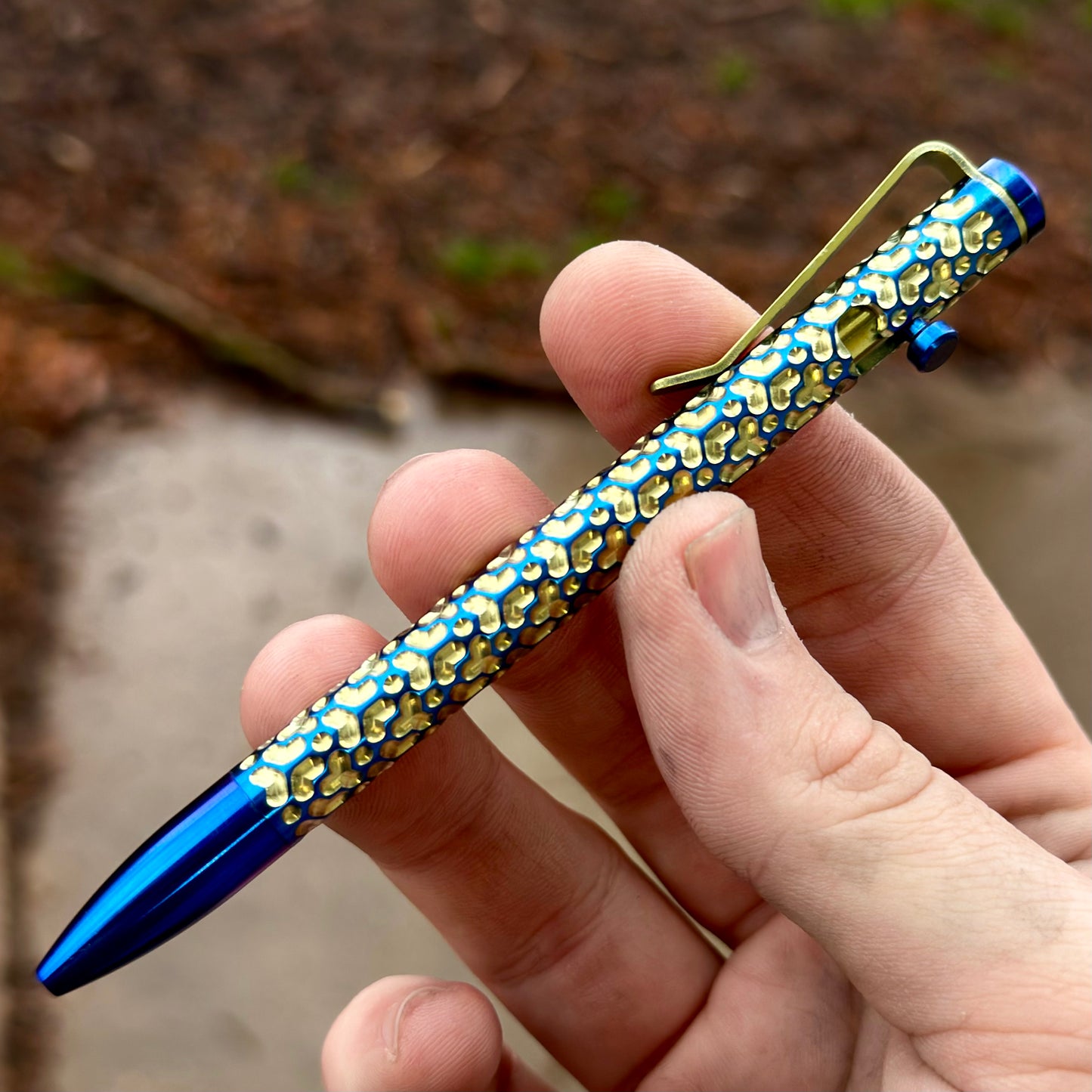 A person grasping a blue and gold designed pen, showcasing elegance and creativity in their writing.