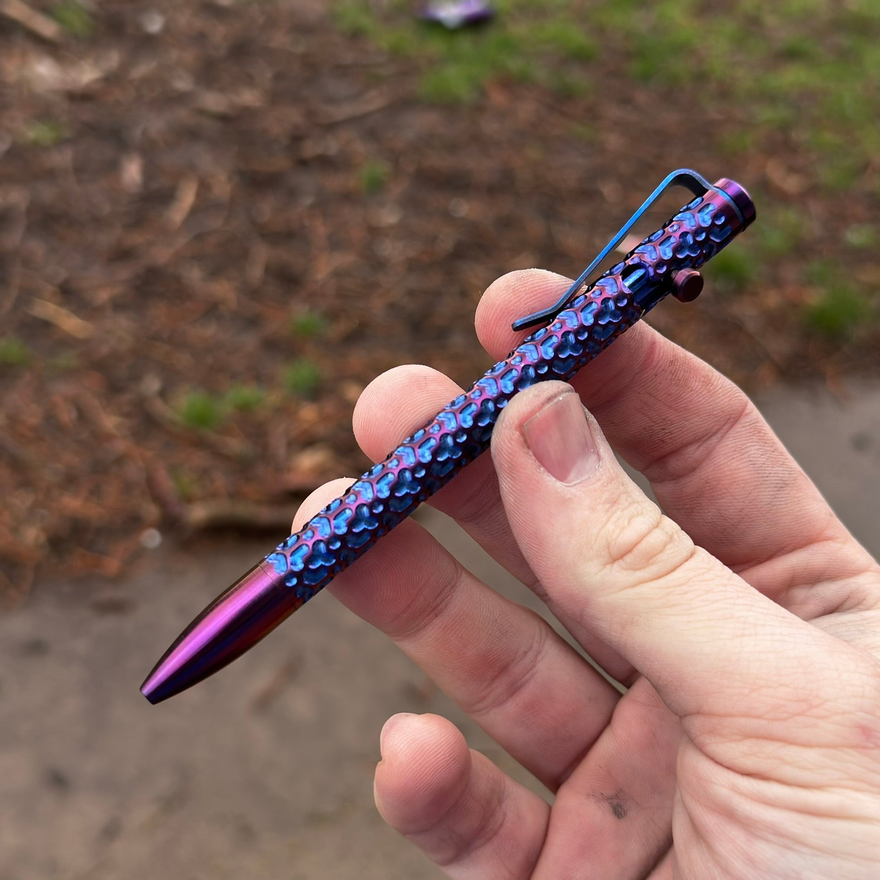 A person grasping a pen featuring a blue and purple design, showcasing creativity and artistic flair.